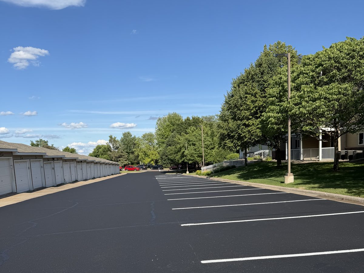 New white parking stall lines on new asphalt beside a row of garages